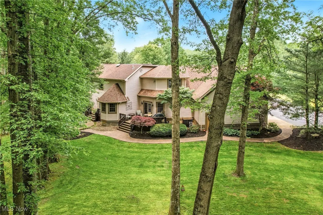 Back of property featuring a wooden deck, a lawn, and roof with shingles