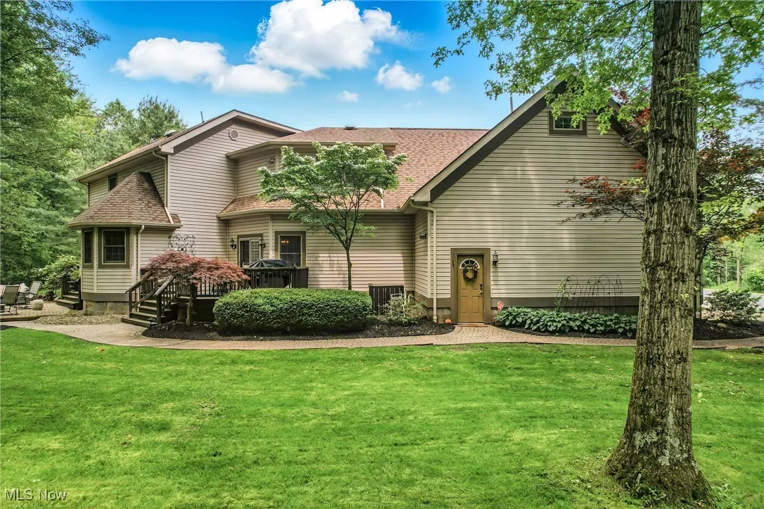 View of front of property featuring a front yard, a shingled roof, and a wooden deck