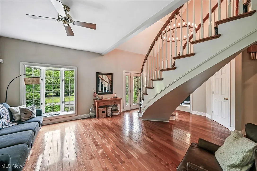 Living room featuring stairway, wood flooring, and a ceiling fan