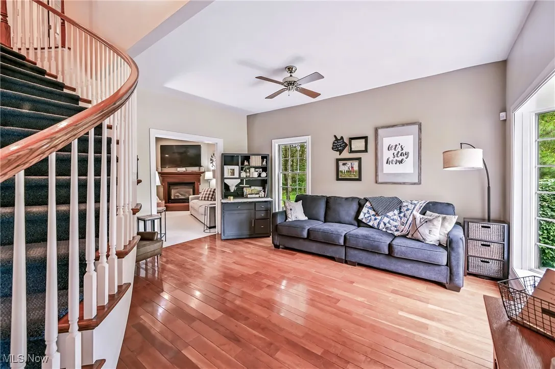 Living room with stairway, wood flooring, a fireplace, and a ceiling fan