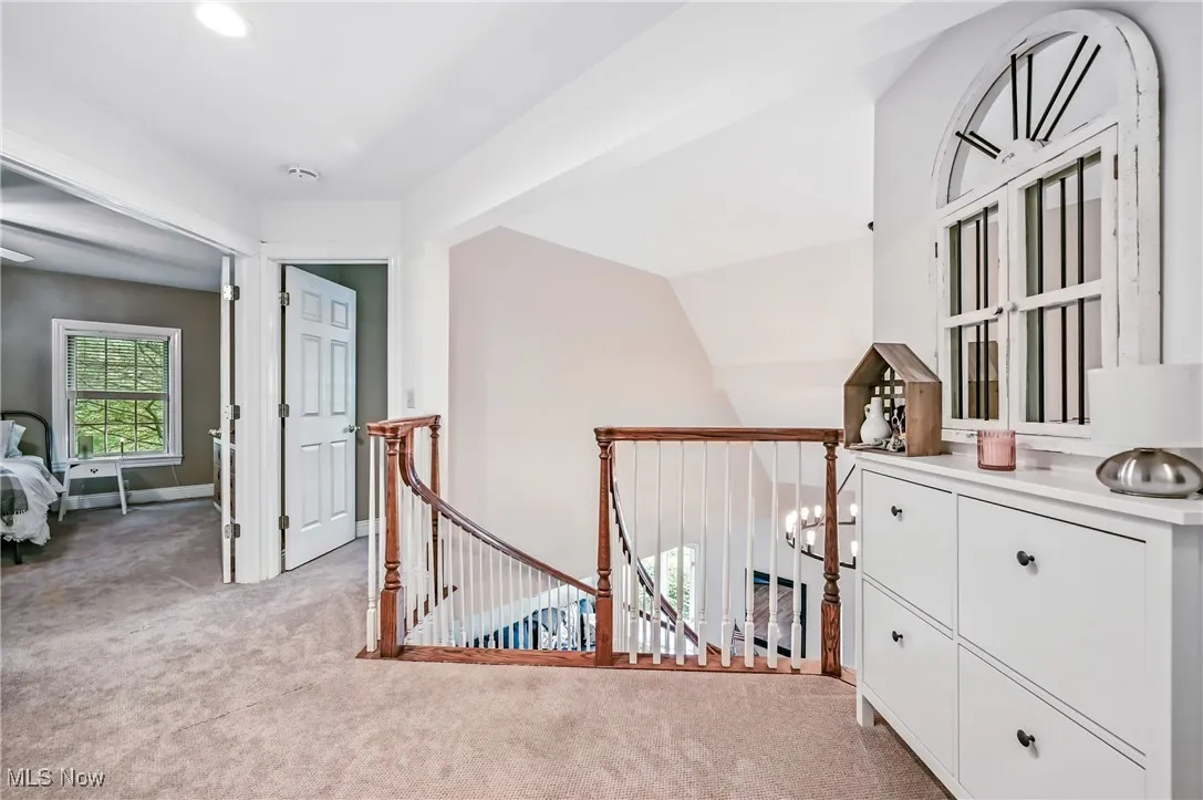 Hall featuring light colored carpet and an upstairs landing