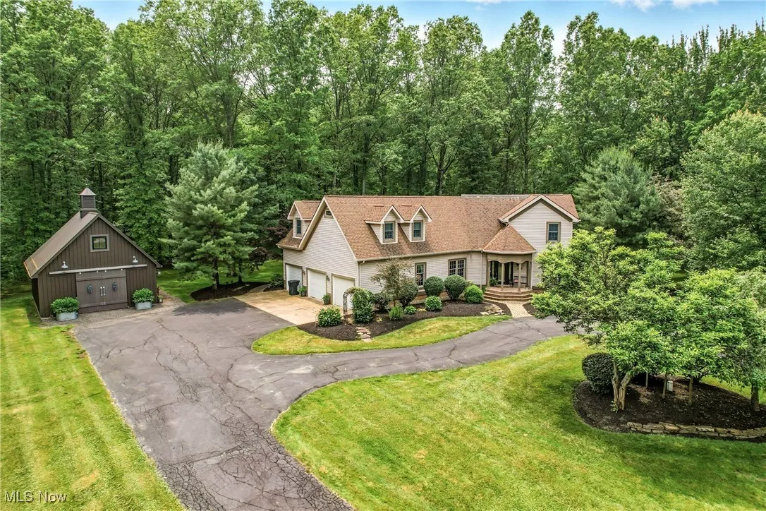 View of front of home with a garage, a front yard, and an outbuilding