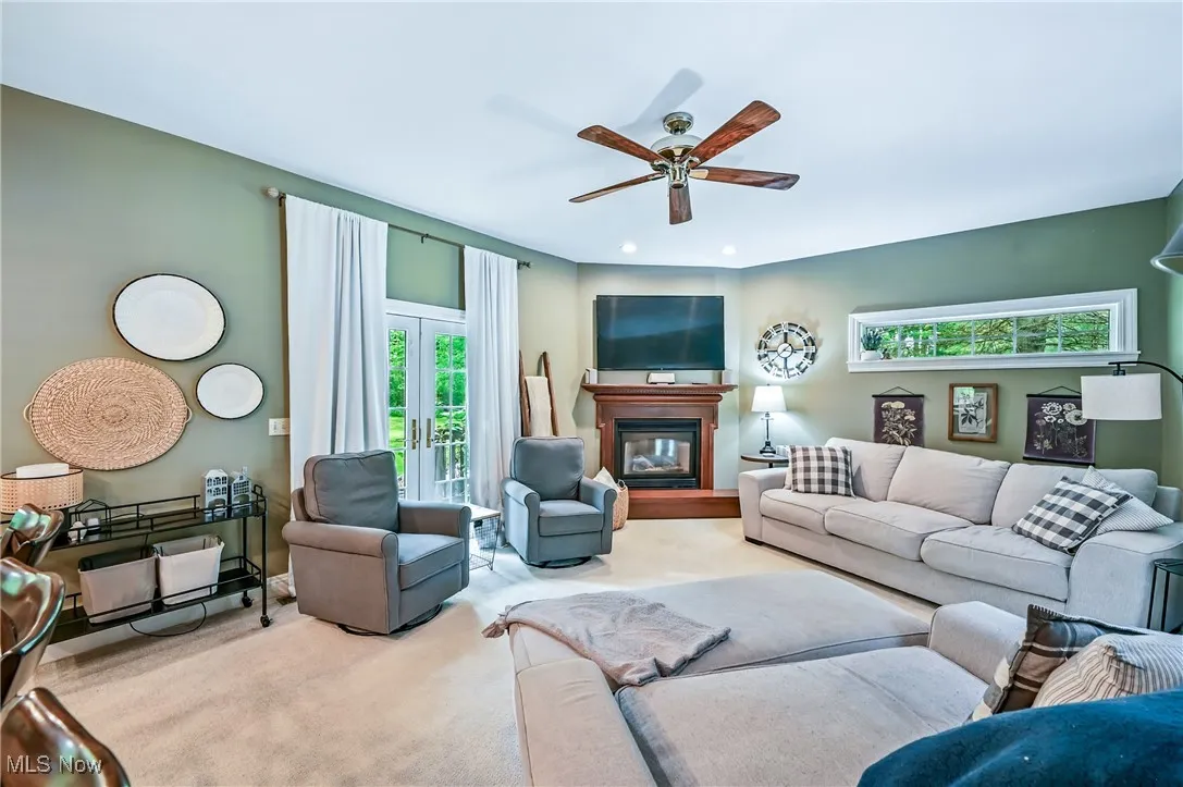 Carpeted living area featuring a ceiling fan, a glass covered fireplace, and recessed lighting