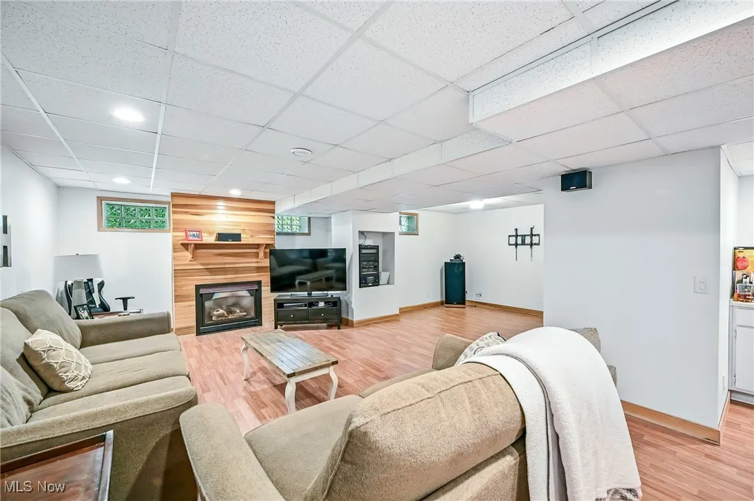 Living area with light wood-type flooring, a large fireplace, a drop ceiling, and recessed lighting