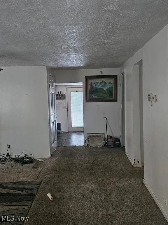 Unfurnished living room with a textured ceiling and carpet