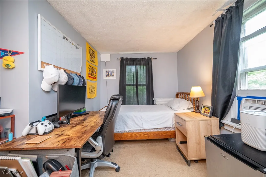 Bedroom with carpet, multiple windows, a textured ceiling, and an office area