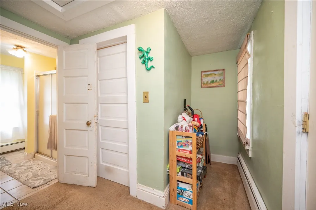 Game room with baseboard heating, carpet, healthy amount of natural light, and a textured ceiling