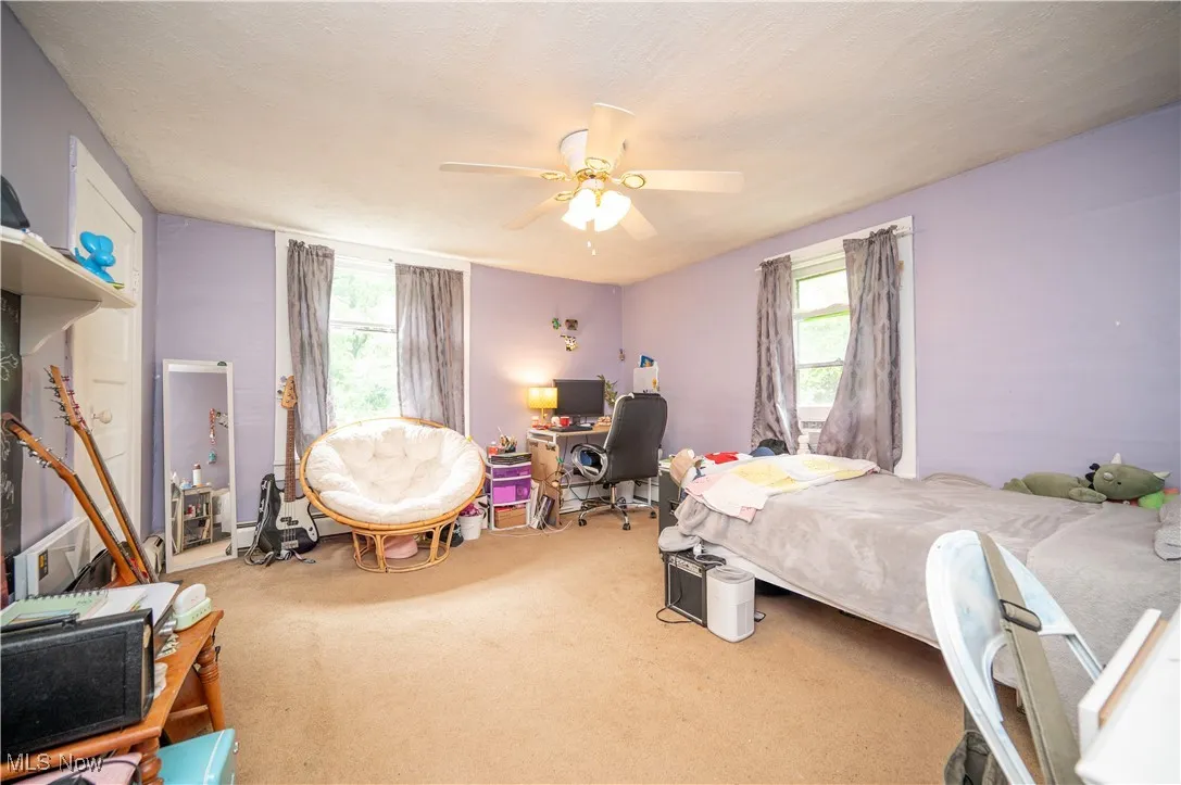 Bedroom with carpet floors, multiple windows, an office area, and a ceiling fan