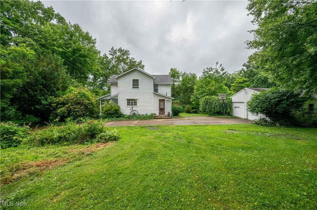 View of green lawn featuring a detached garage and an outbuilding