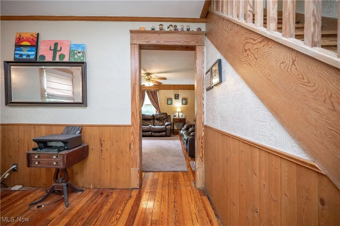 Hallway featuring a wainscoted wall, hardwood / wood-style floors, and wood walls