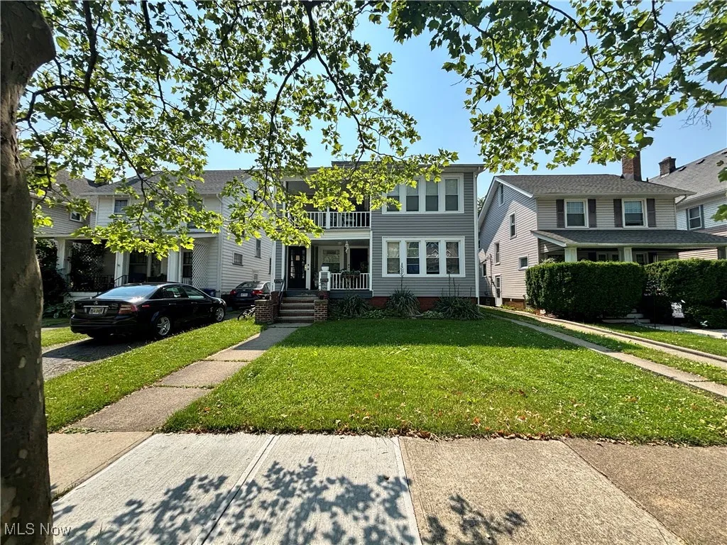 Townhome / multi-family property with a balcony, a front lawn, and covered porch