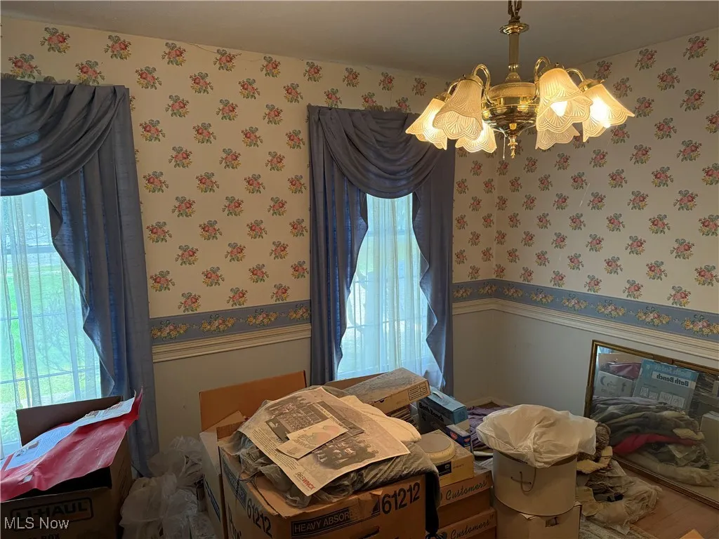 Dining room featuring wallpapered walls, multiple windows, and wainscoting
