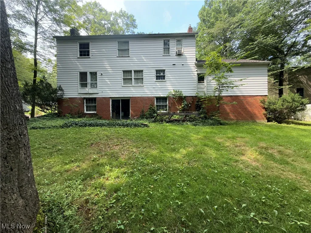 Back of house featuring a yard, brick siding, and a chimney