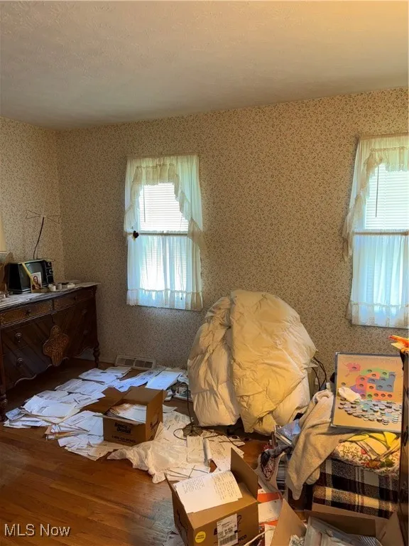 Bedroom featuring wallpapered walls and wood finished floors