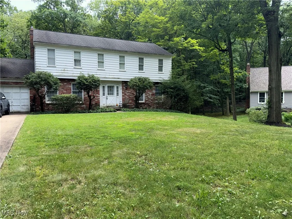 View of front of home featuring an attached garage, driveway, a front yard, and brick siding