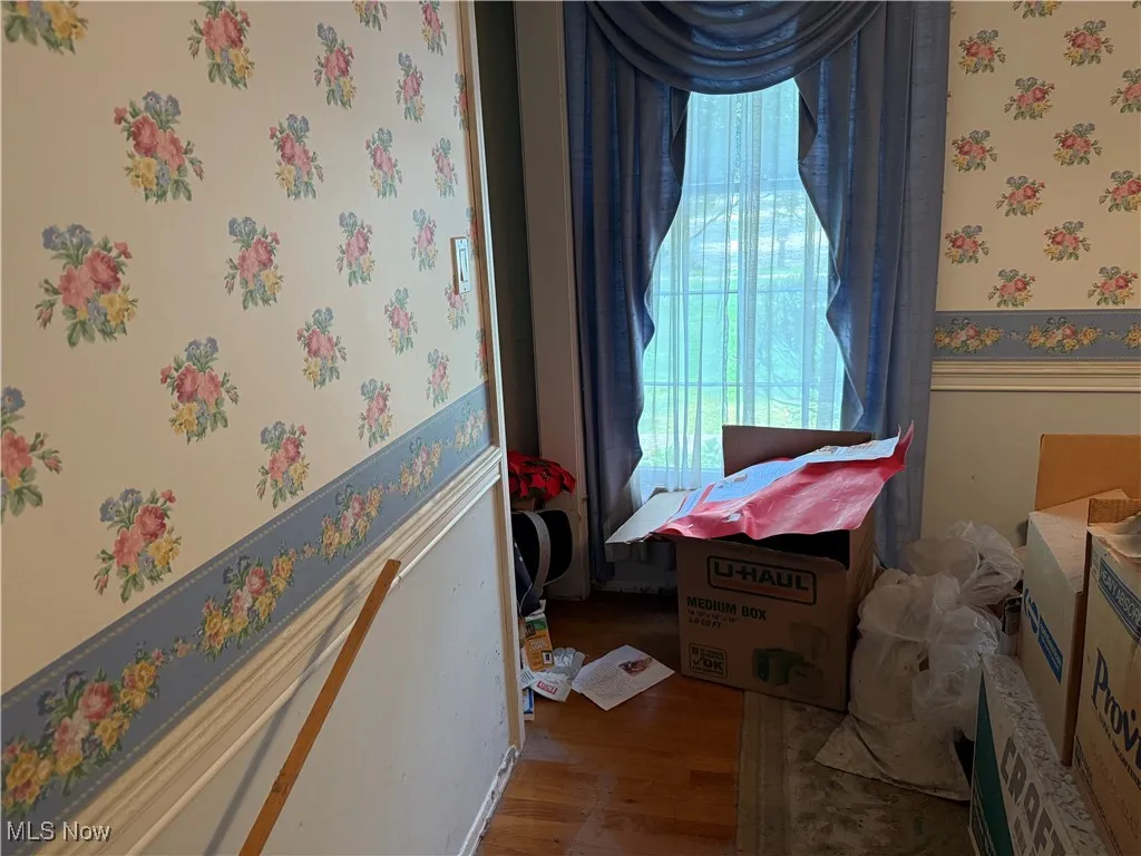 Dining room featuring wallpapered walls, wood finished floors, and a wainscoted wall