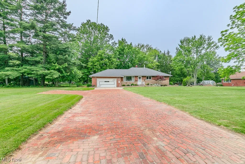 View of front of property featuring a garage, decorative driveway, a front yard, and brick siding