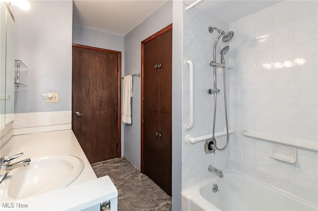 Bathroom featuring shower / tub combination, vanity, and marble finish flooring