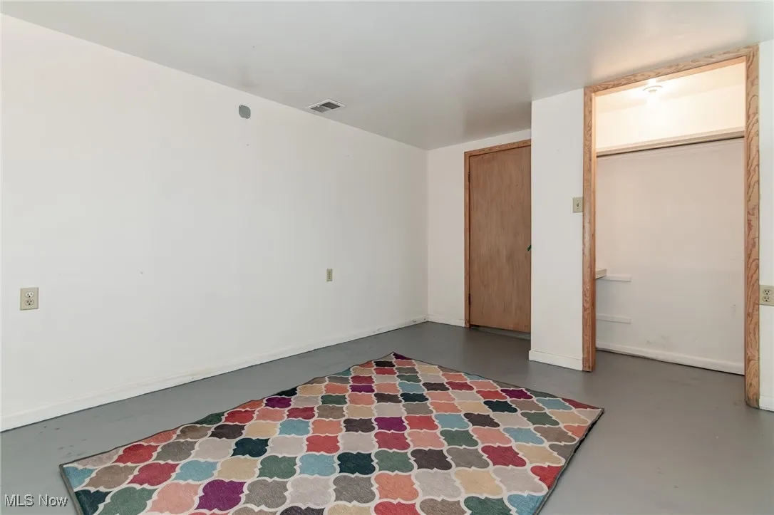 Unfurnished bedroom featuring finished concrete floors and baseboards