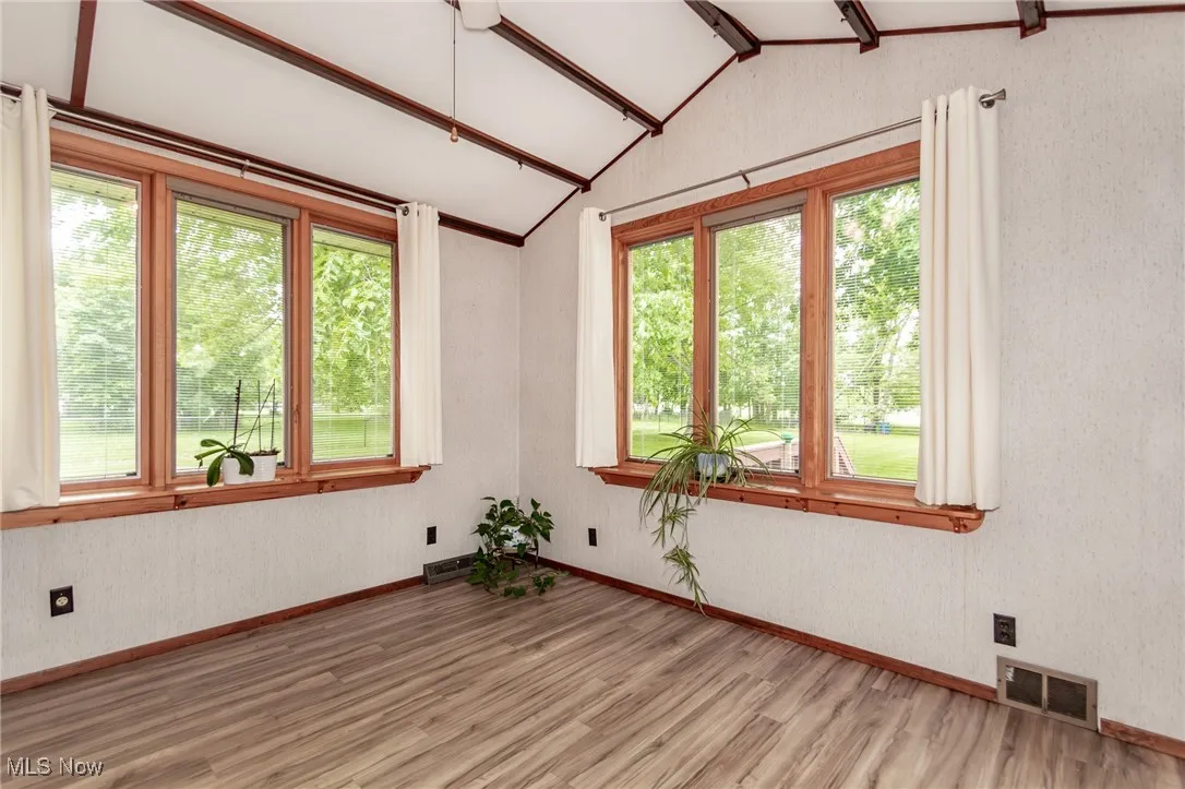 Fmaily room featuring healthy amount of natural light, wood finished floors, and vaulted ceiling