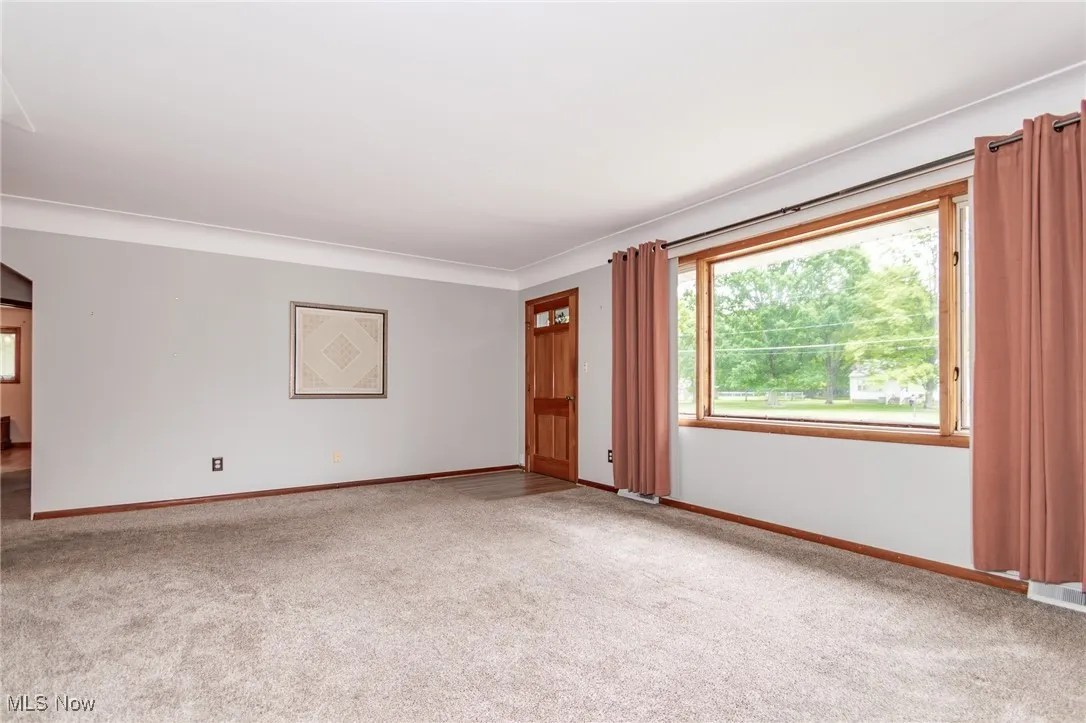 Living room featuring carpet flooring, front door and front window with natural lighting