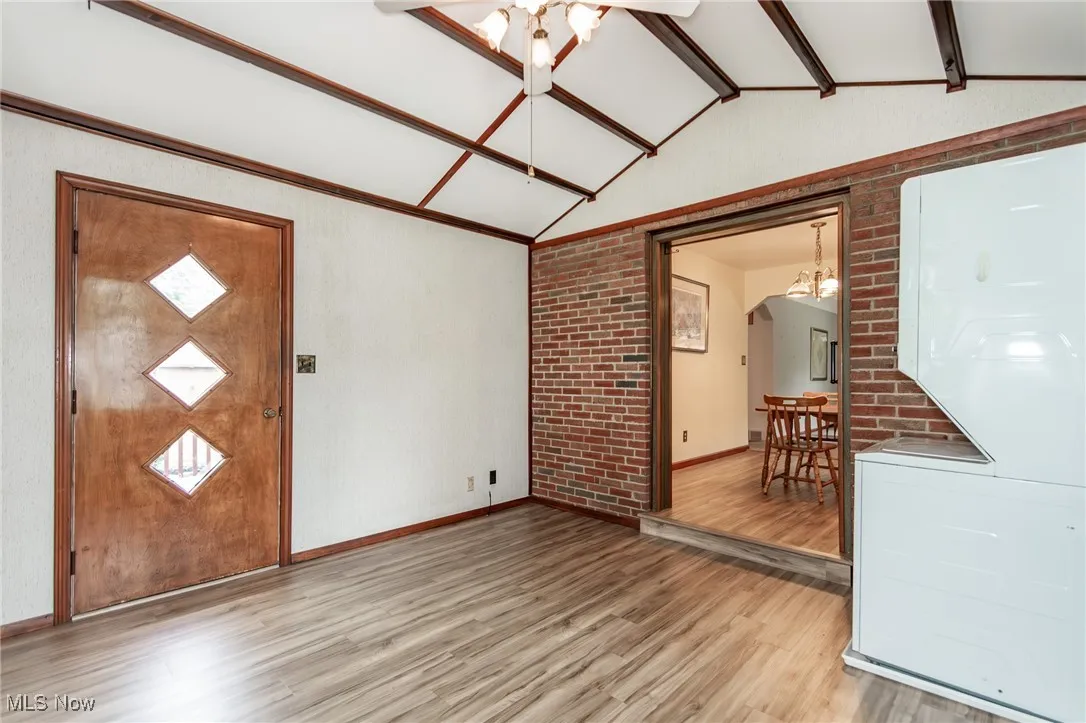 Family room with light wood-style floors, stacked washer / drying machine, and arched walkways