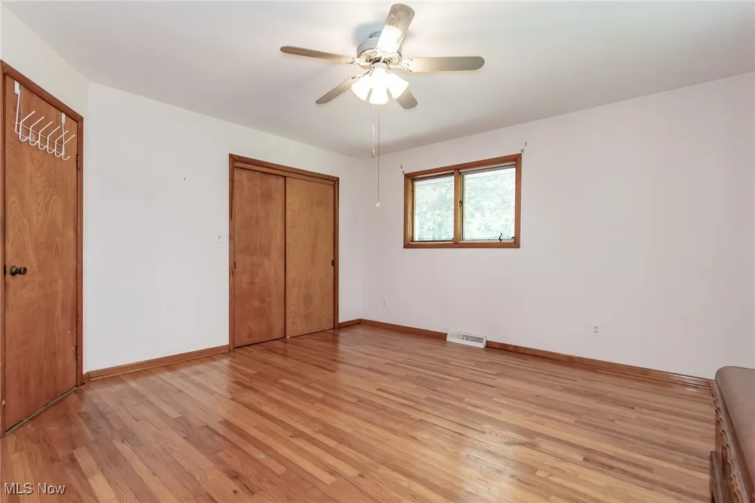 Unfurnished bedroom with light wood-type flooring, ceiling fan, and a closet