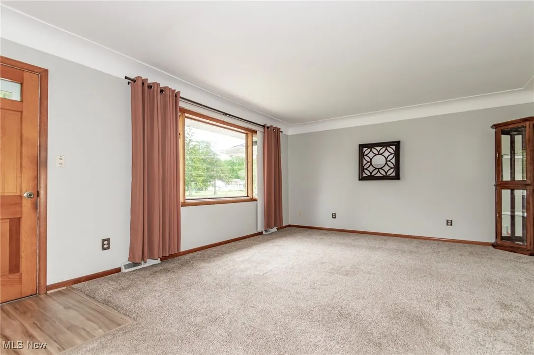 Front carpeted living room with view of front door and large window providing natural light.