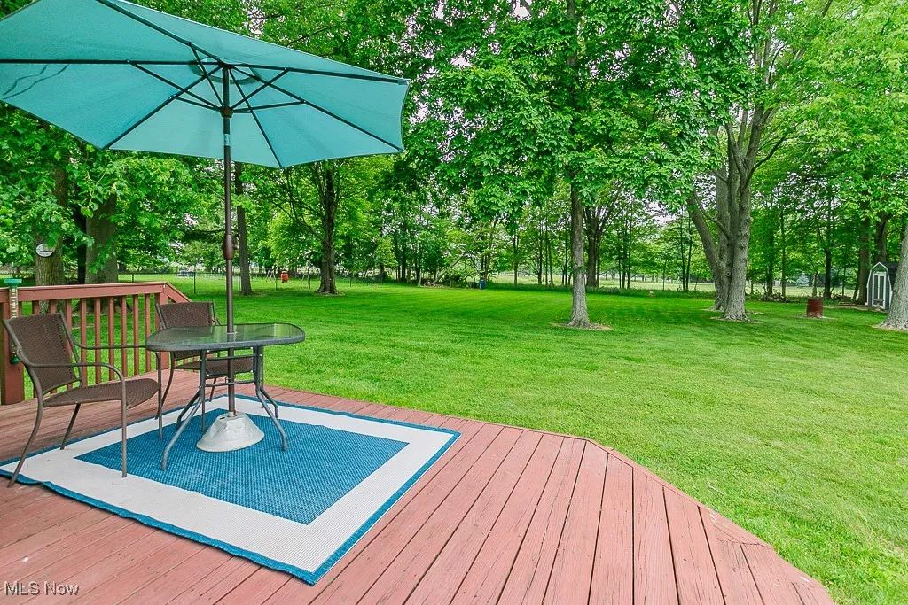 Wooden deck with a yard, view of scattered trees, and outdoor dining area