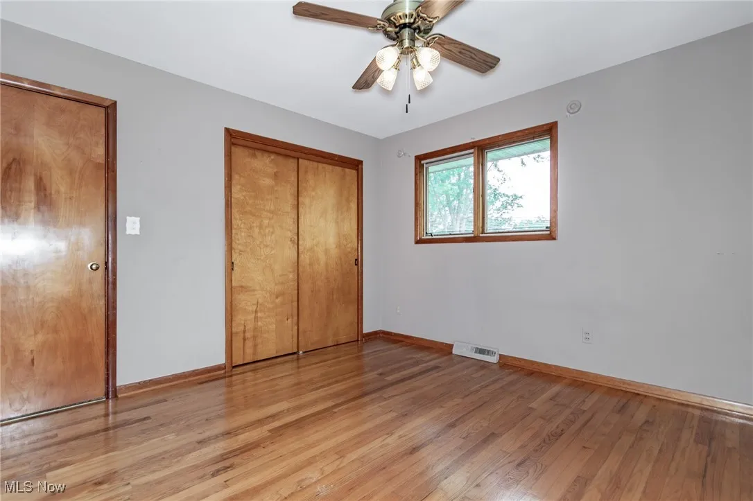 Unfurnished bedroom featuring light wood finished floors, a closet, and a ceiling fan