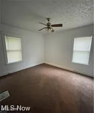 Empty room with carpet floors, a ceiling fan, and baseboards