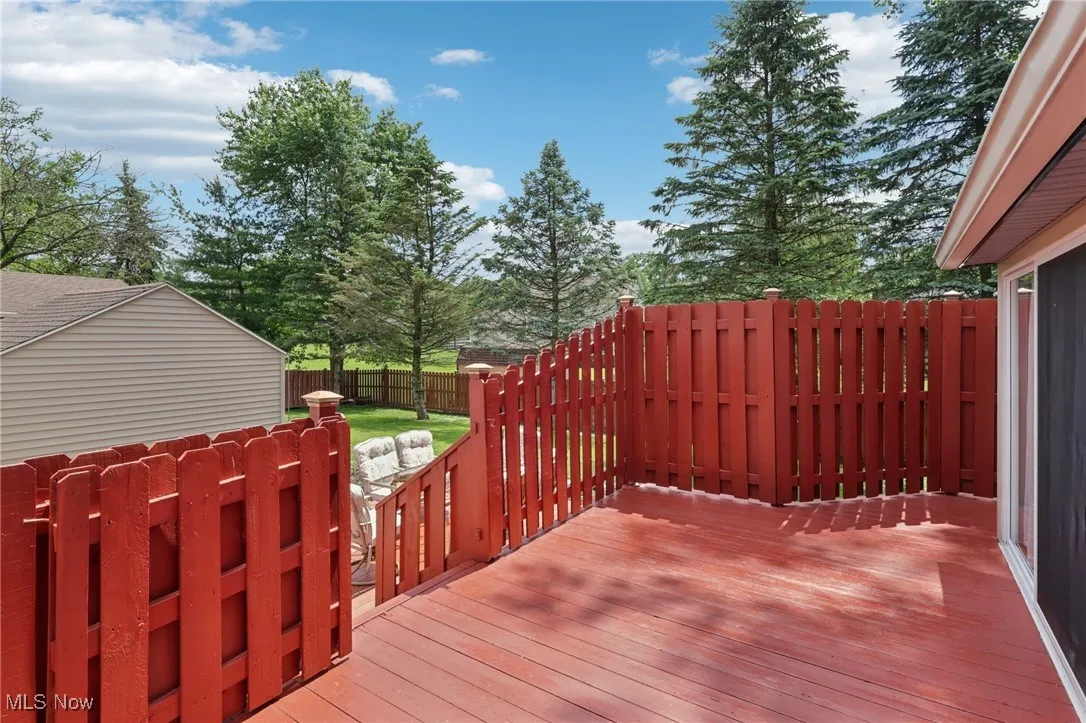 Wooden terrace with a fenced backyard