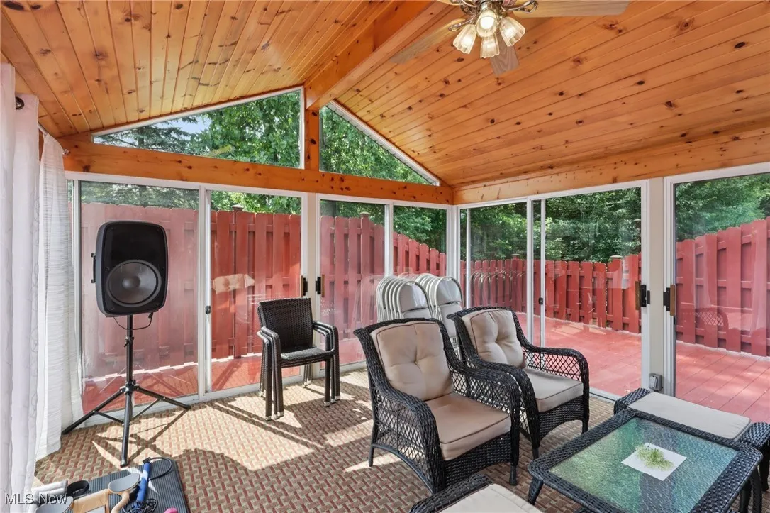 3 seasons room with a ceiling fan and vaulted ceiling