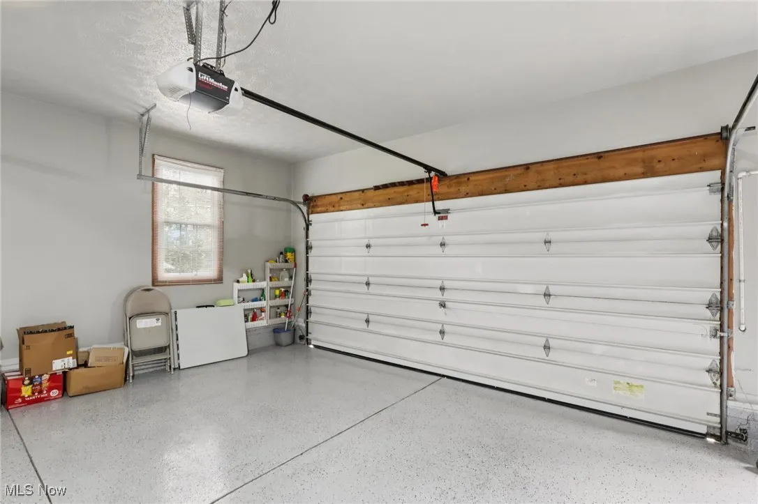 Garage featuring a garage door opener and epoxy flooring.
