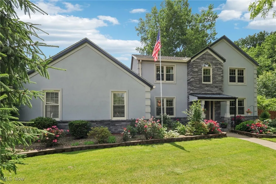 View of front of home with stucco siding, stone siding, and a front yard