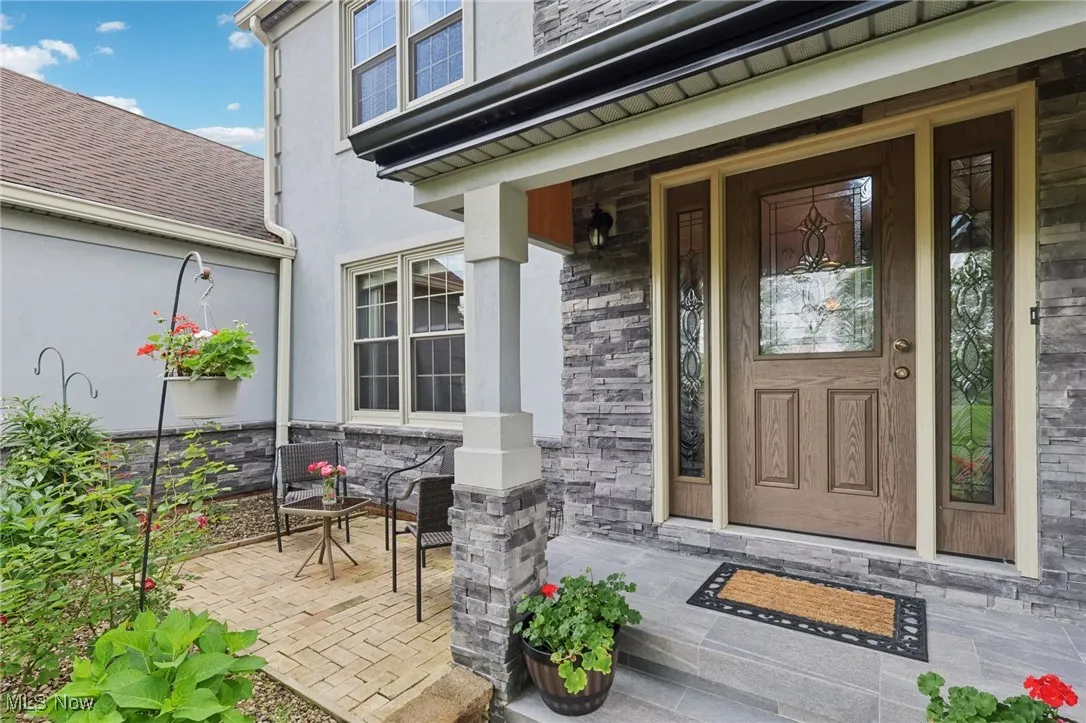 Entrance to property with a porch, stucco and stone siding