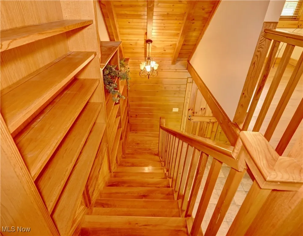 Stairway with a chandelier, a relaxing sauna, and wooden walls