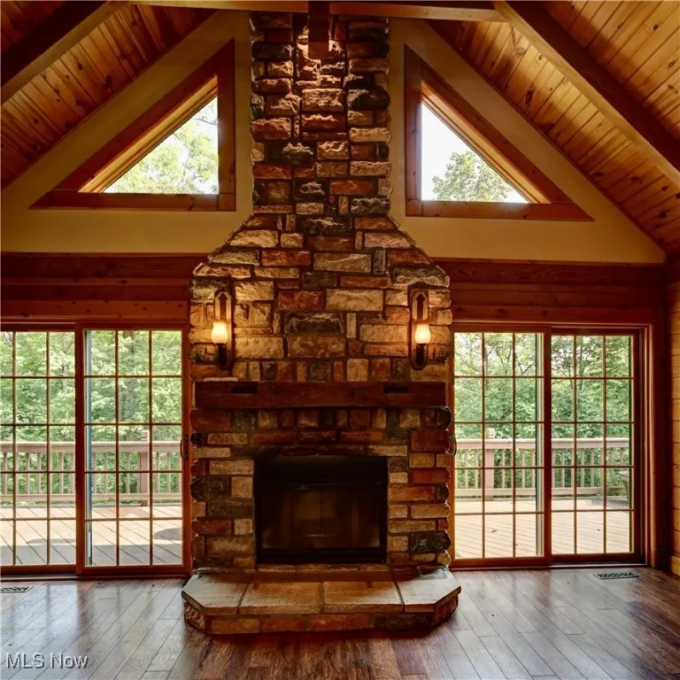 Detailed view of wood finished floors, a stone fireplace, and a wood ceiling with exposed beams