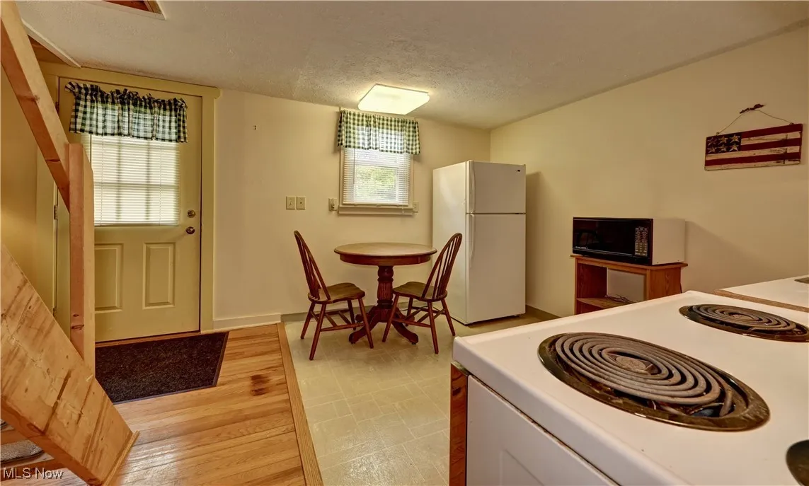Kitchen with freestanding refrigerator, range, black microwave, a textured ceiling, and light countertops