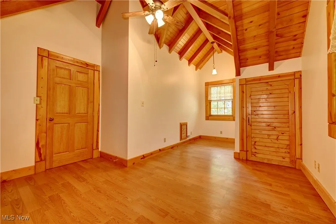 Unfurnished room with light wood-style floors, a wood ceiling with exposed beams, ceiling fan, and high vaulted ceiling