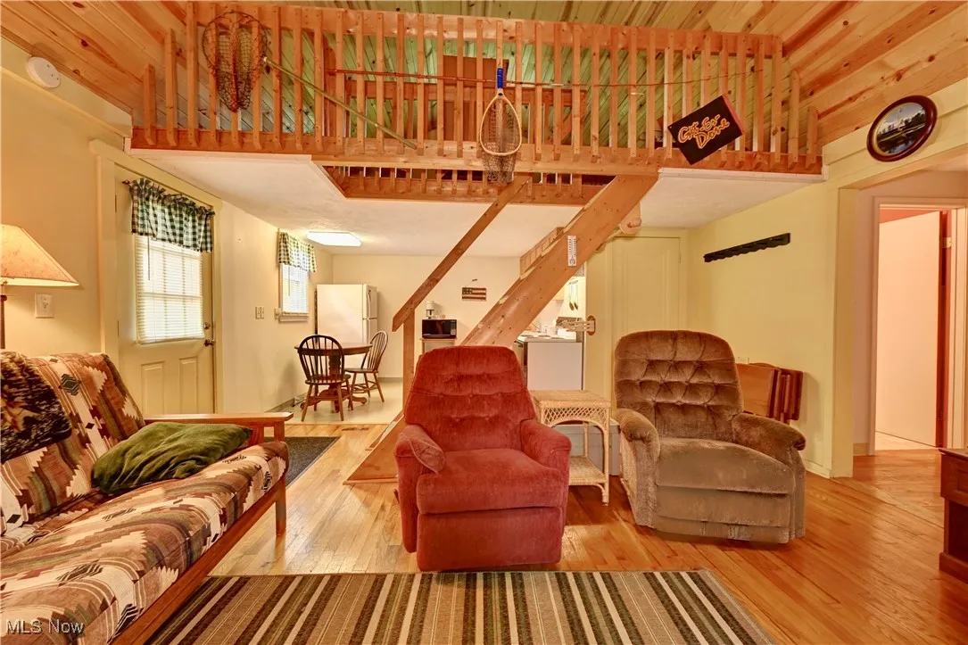 Living area with stairway, wood finished floors, a towering ceiling, and wood ceiling