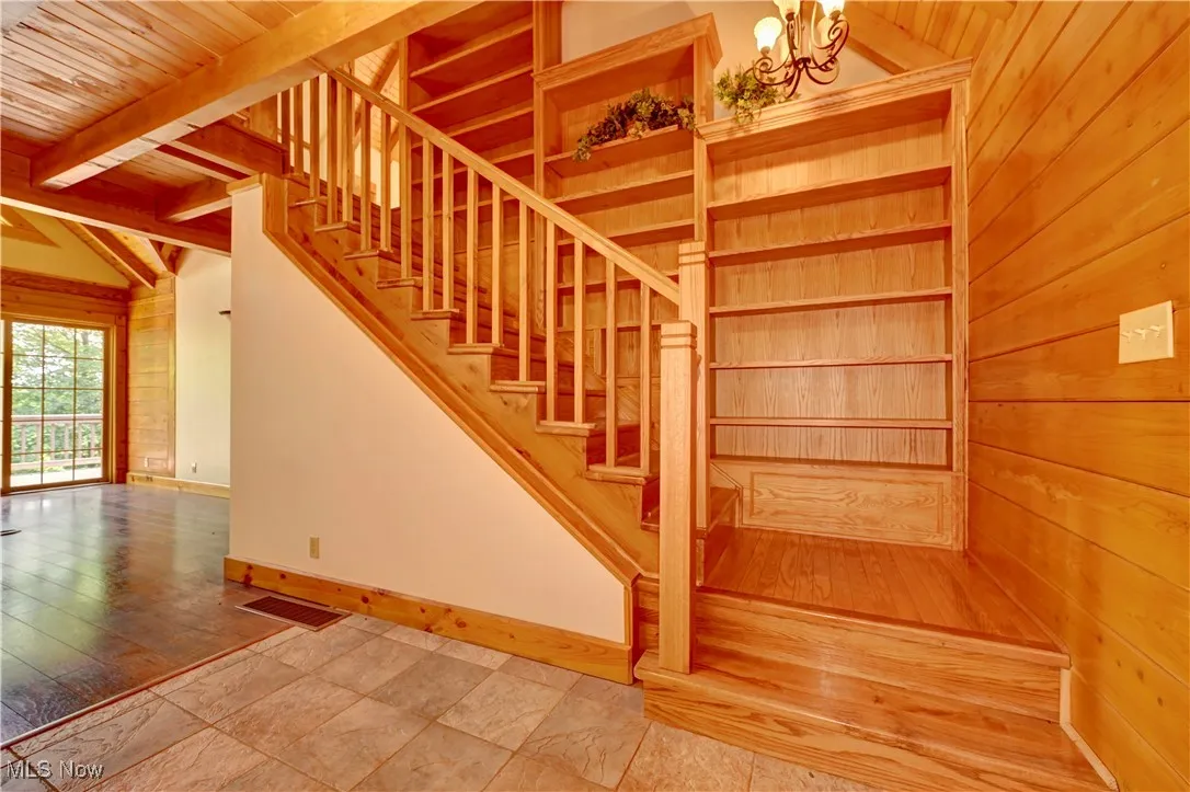 Stairway featuring wood ceiling, a chandelier, and wood walls