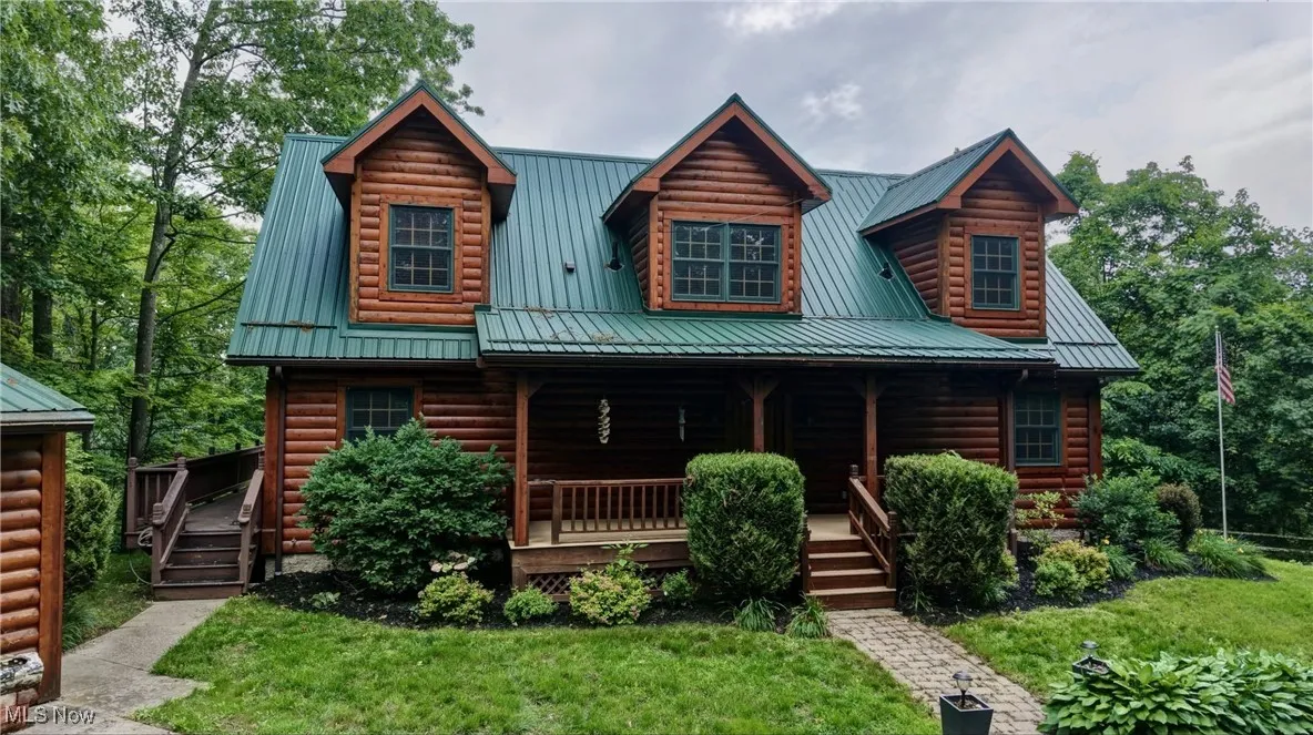 Log cabin with a porch, a metal roof, log veneer siding, and a front lawn