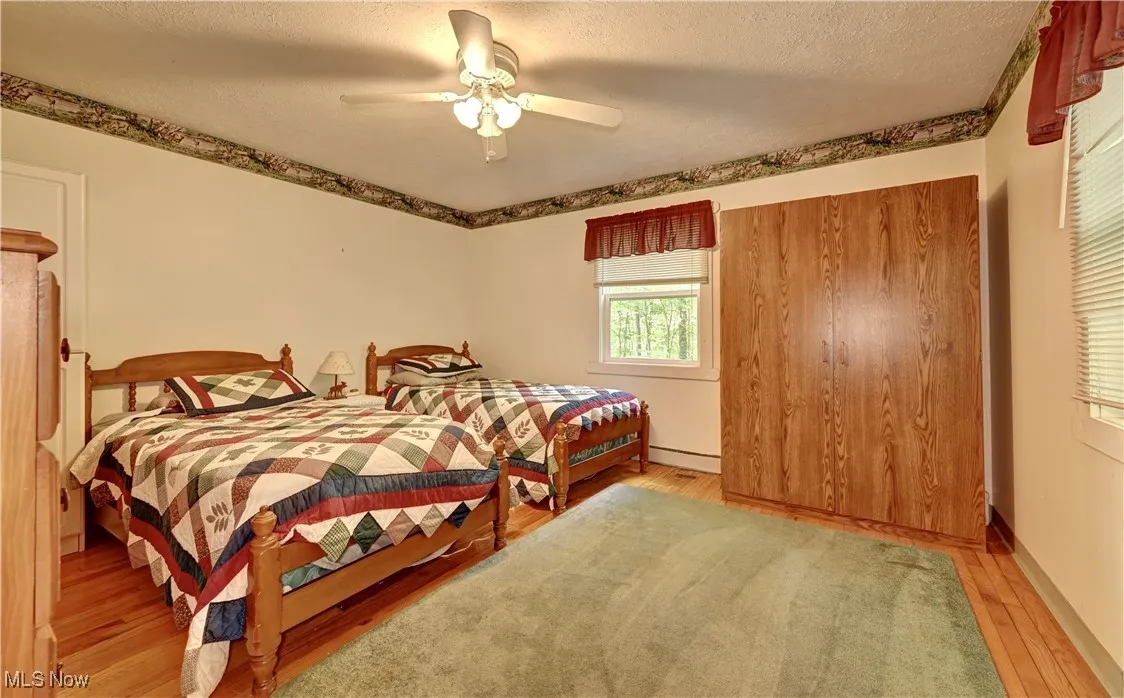 Bedroom with light wood-style flooring, a textured ceiling, ceiling fan, and a baseboard radiator