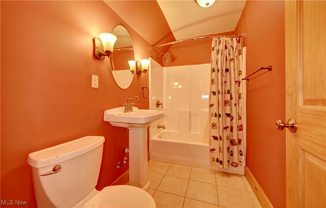 Bathroom featuring tile patterned flooring, shower / bath combo, and vaulted ceiling