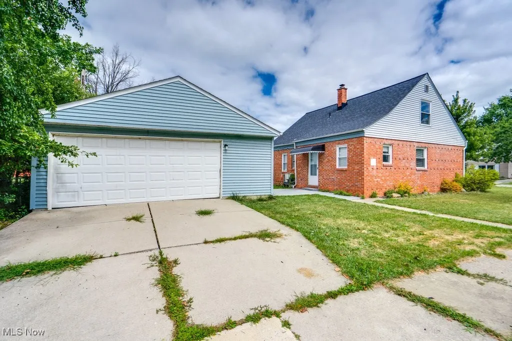 View of front of home featuring an outbuilding, brick siding, a front lawn, and a garage