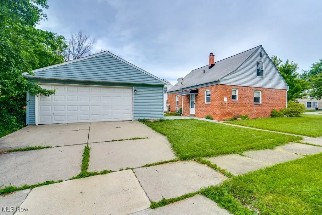View of front of house featuring a front yard, brick siding, a garage, and a chimney