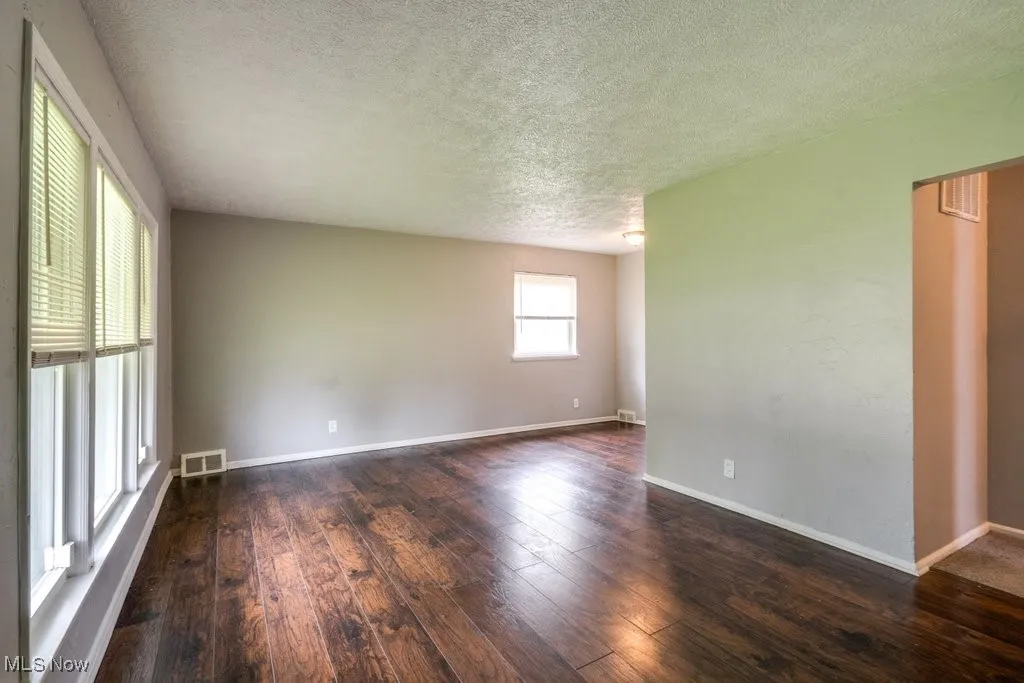 Unfurnished room with a textured ceiling and dark wood finished floors