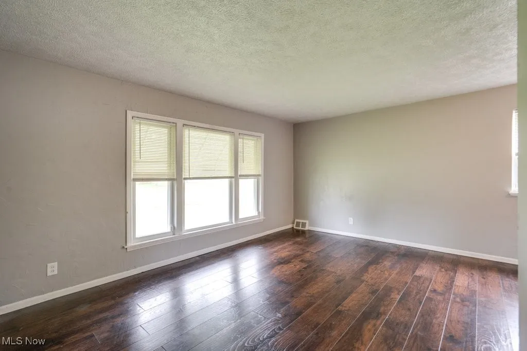Empty room with dark wood-type flooring and a textured ceiling