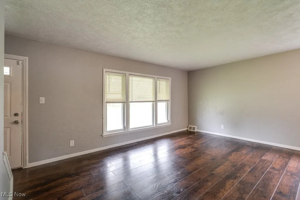 Unfurnished room with dark wood-type flooring and a textured ceiling